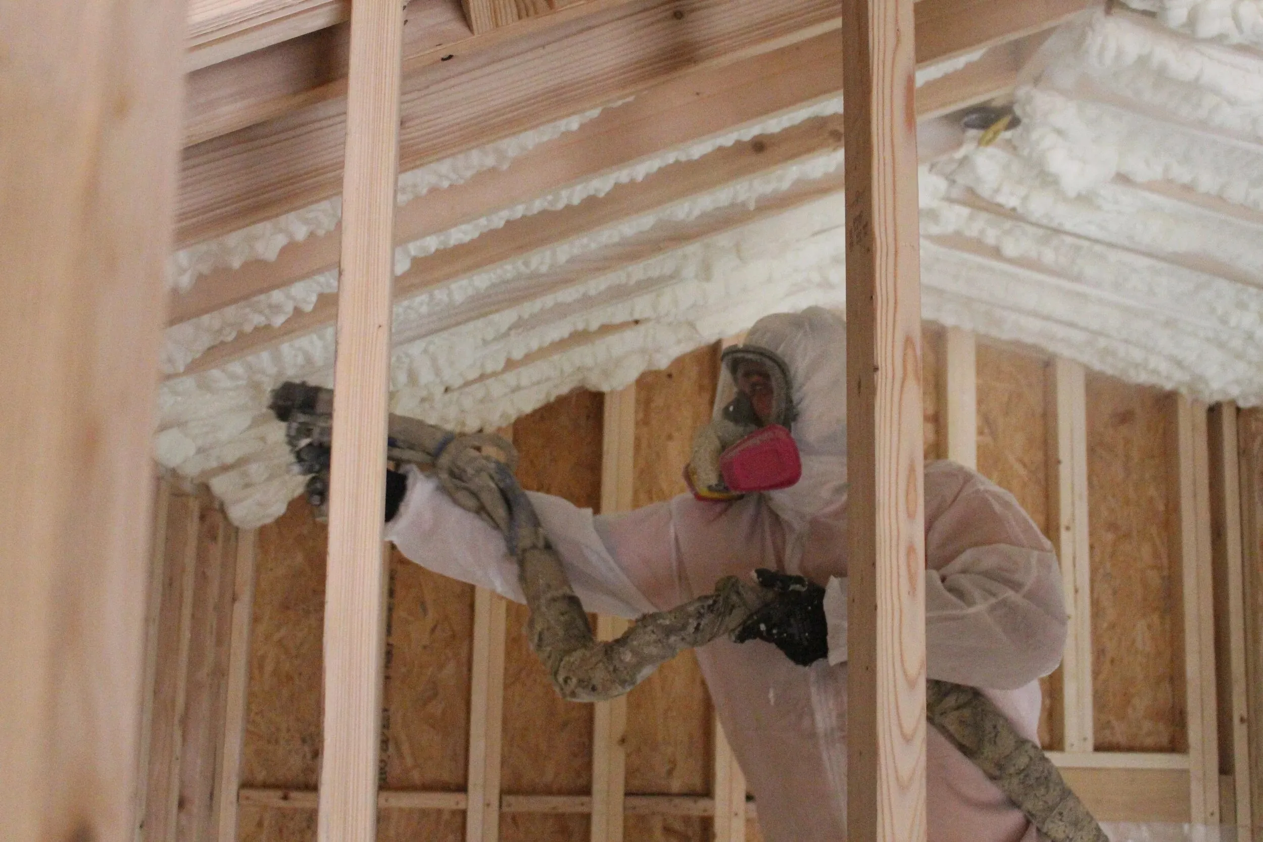 Installer spraying foam between wall studs